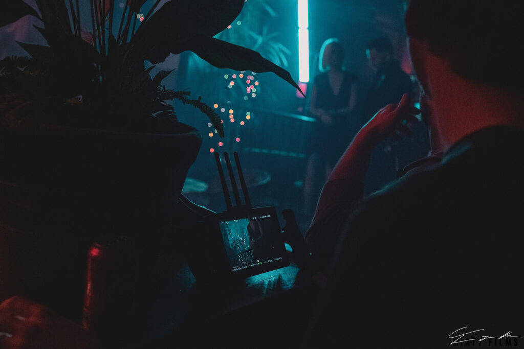 Behind the scenes crew reviewing footage on monitor during moody cinematic video production