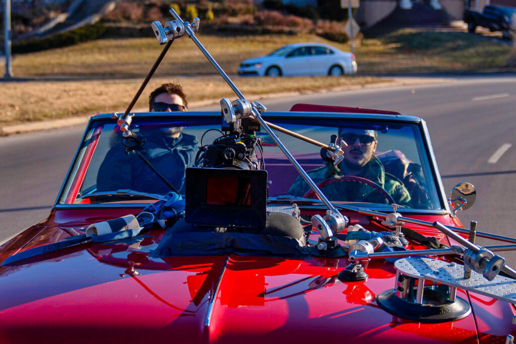 Car mounted camera rig capturing driving footage during cinematic video production
