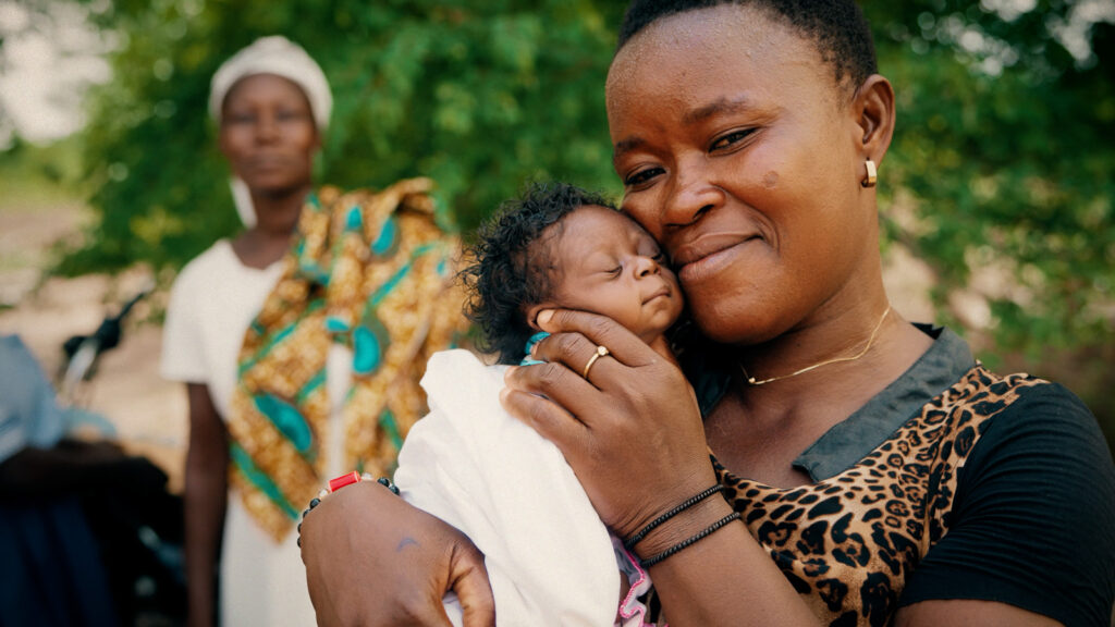 Cinematic video thumbnail of mother holding sleeping infant outdoors