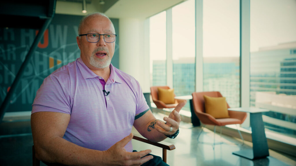 Cinematic interview subject speaking on camera in a contemporary office lounge, filmed by Hiatt Films