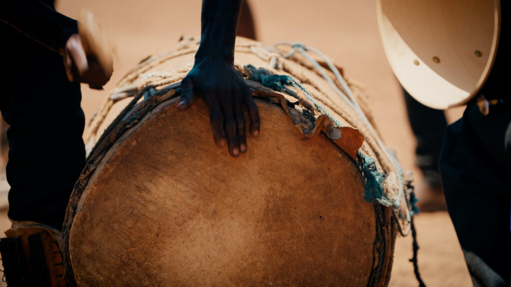 Cinematic shot of hands playing a traditional drum during a cultural performance, filmed by Hiatt Films