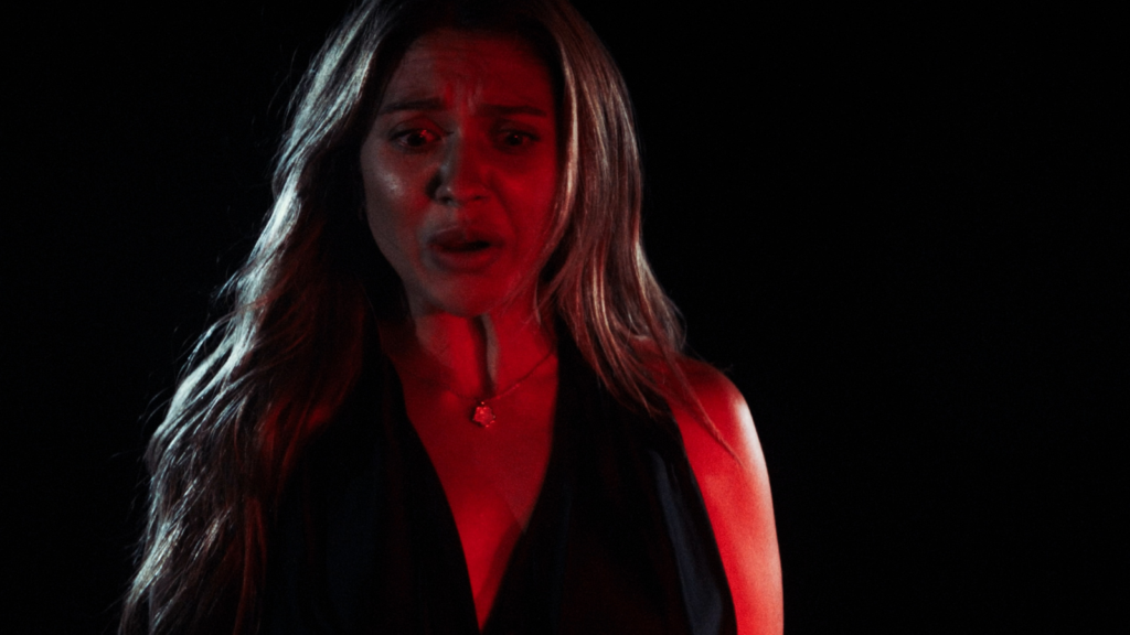 Woman illuminated by red lighting during dramatic performance scene