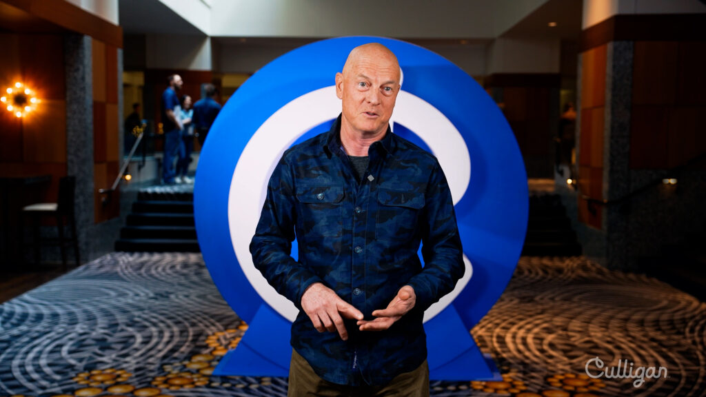 Speaker presenting at Culligan corporate event in front of branded backdrop
