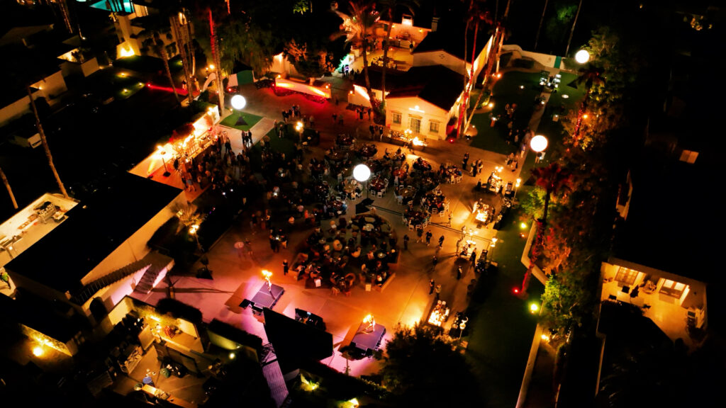 Aerial view of outdoor nighttime event with warm lighting and crowd gathering