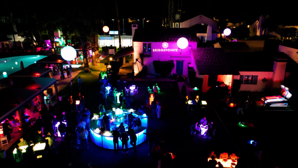 Aerial view of colorful outdoor event with neon lighting and guests