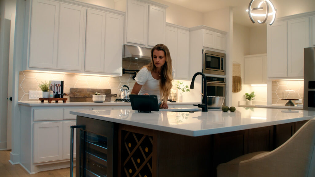 Woman using tablet in modern luxury kitchen with island and warm lighting